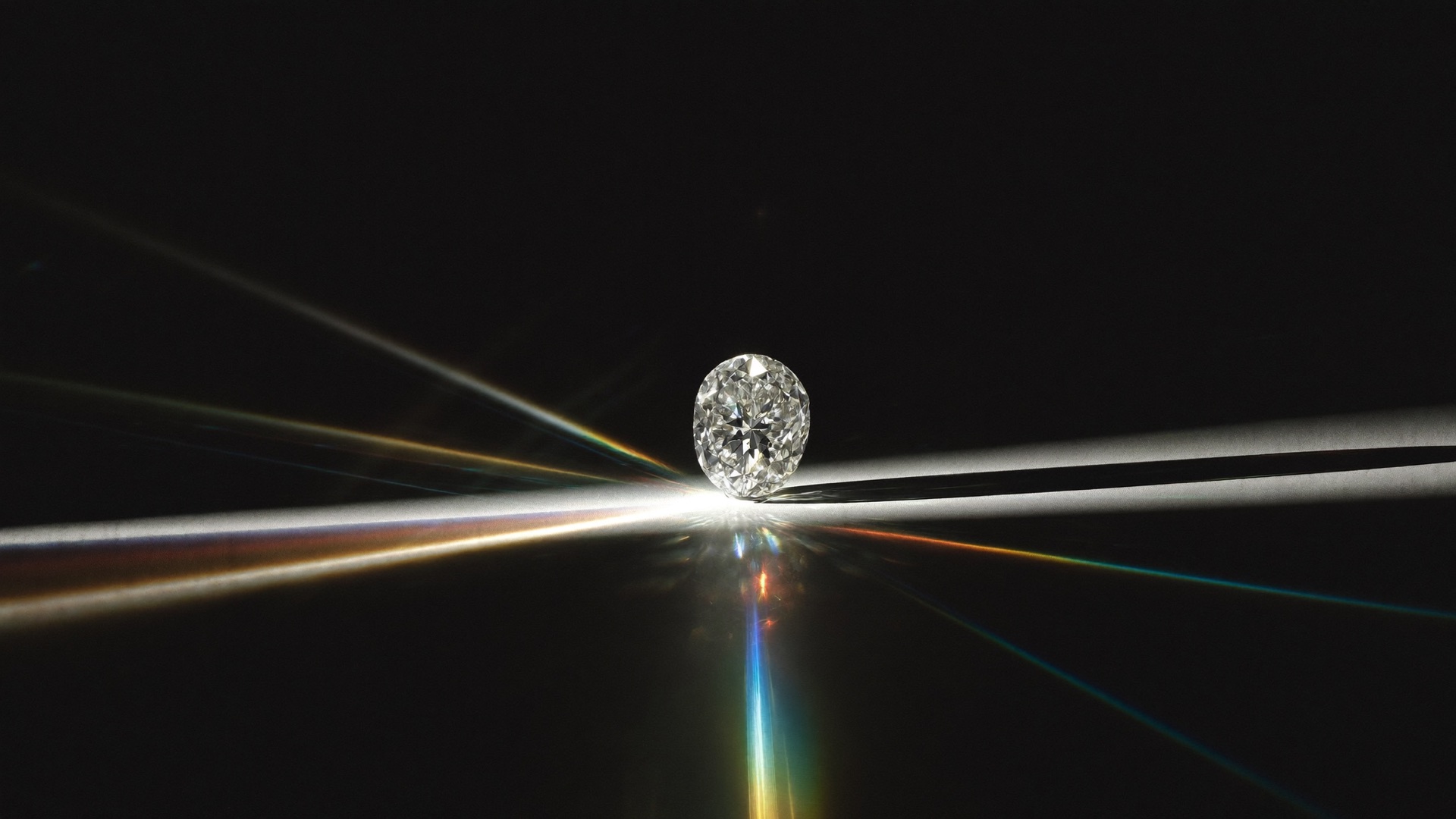 Brilliant-cut diamond splitting a beam of light into a spectrum on black glass