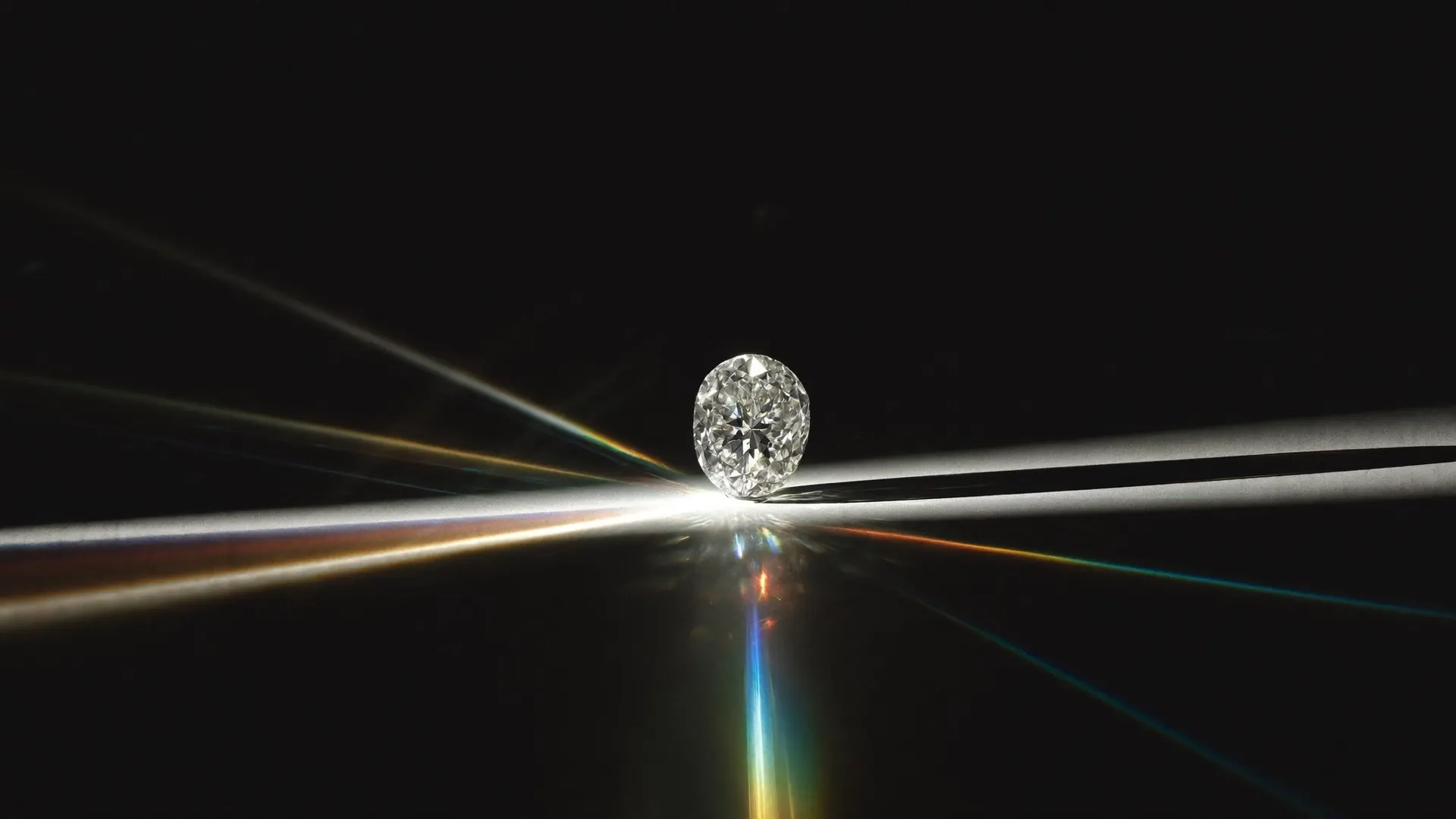 Brilliant-cut diamond splitting a beam of light into a spectrum on black glass