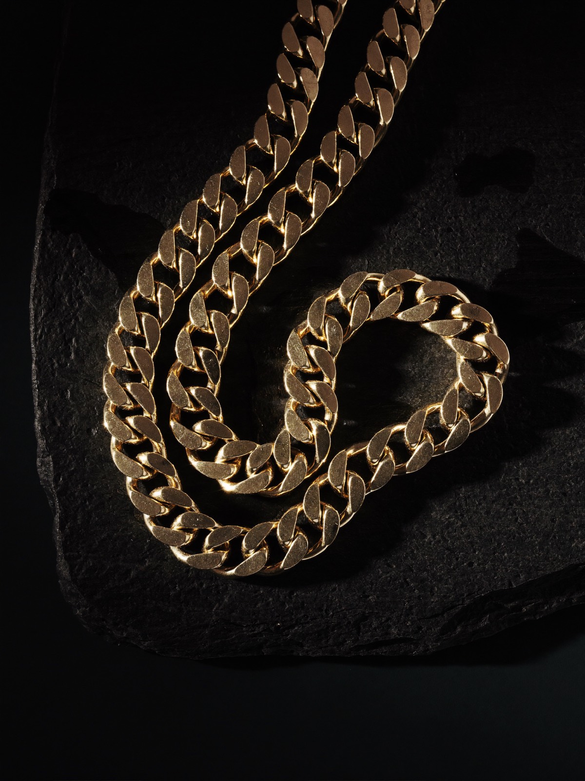 Gold Cuban link chain on black slate