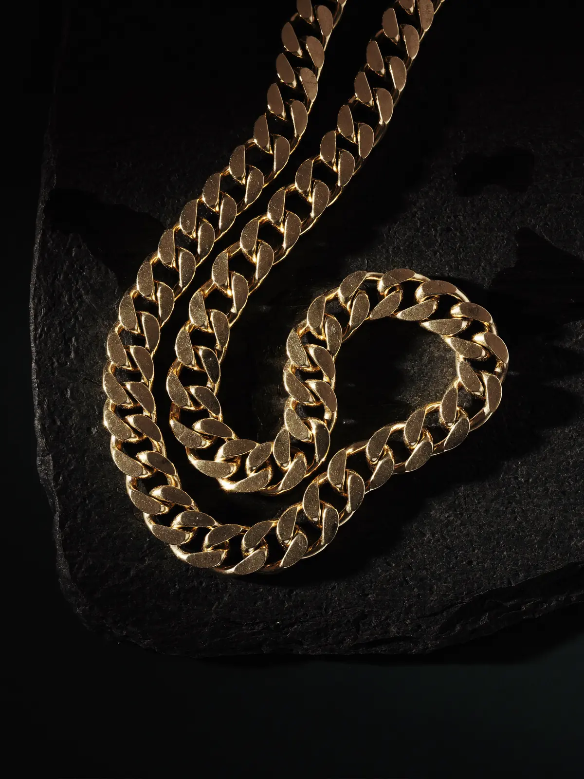 Gold Cuban link chain on black slate