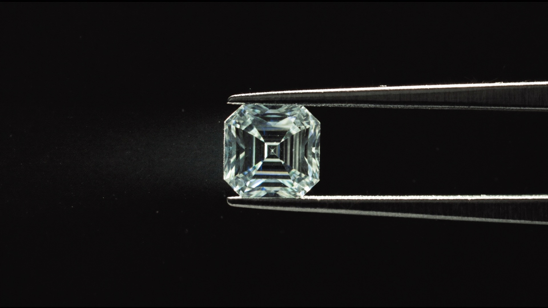 Emerald-cut diamond held in jeweller's tweezers